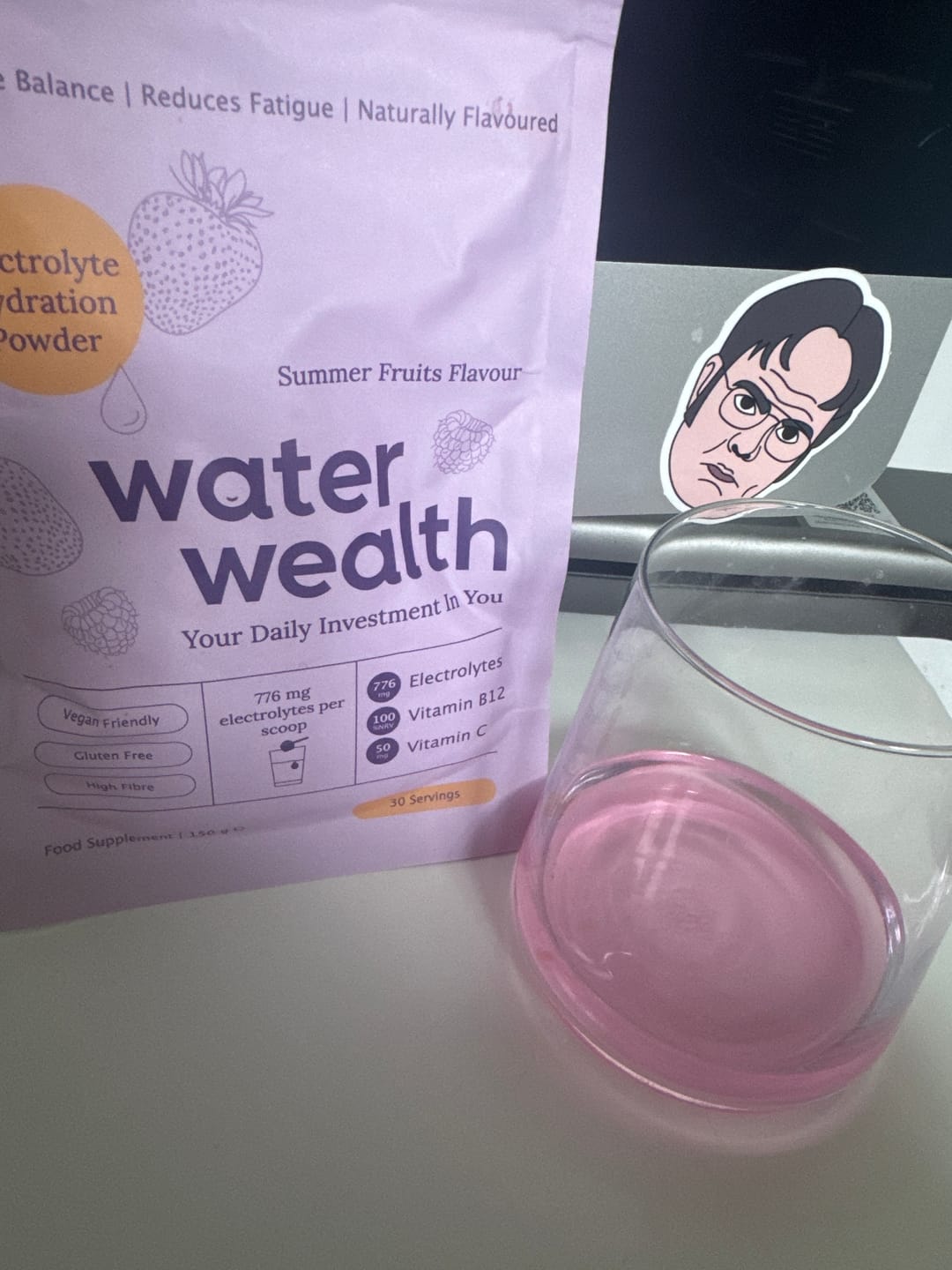 Water Wealth electrolyte powder pack with glass of mixed pink summer fruits drink - gut health hydration supplement ready to enjoy