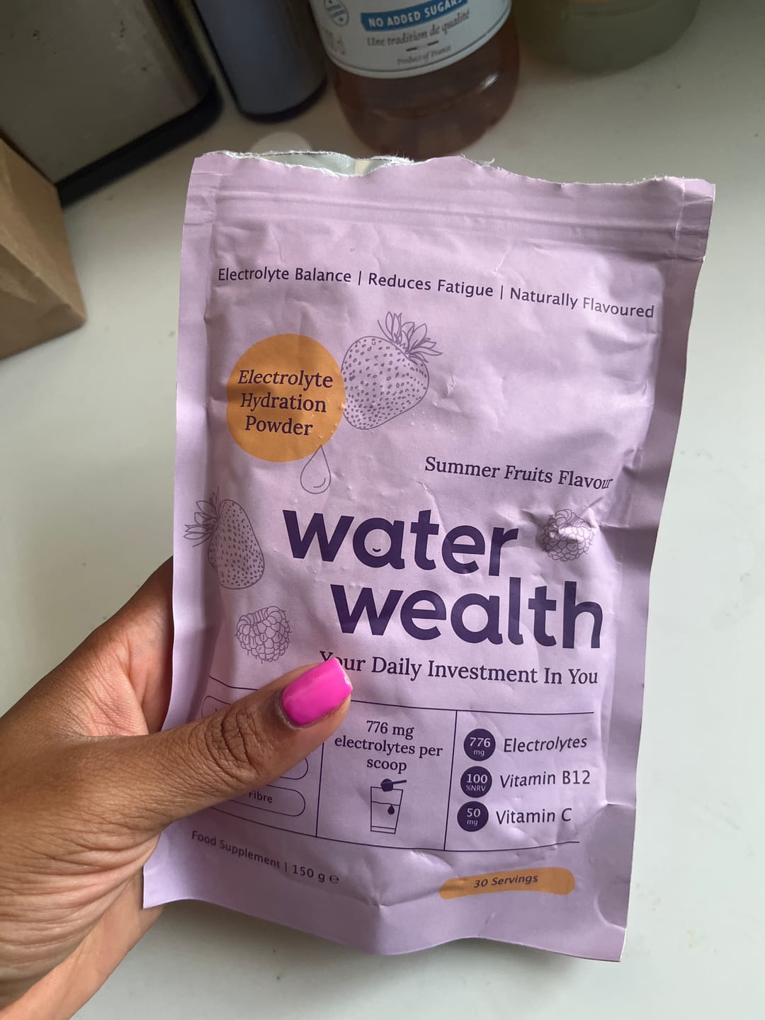 Hand holding Water Wealth electrolyte hydration powder pack - customer photo showing summer fruits flavour gut health supplement